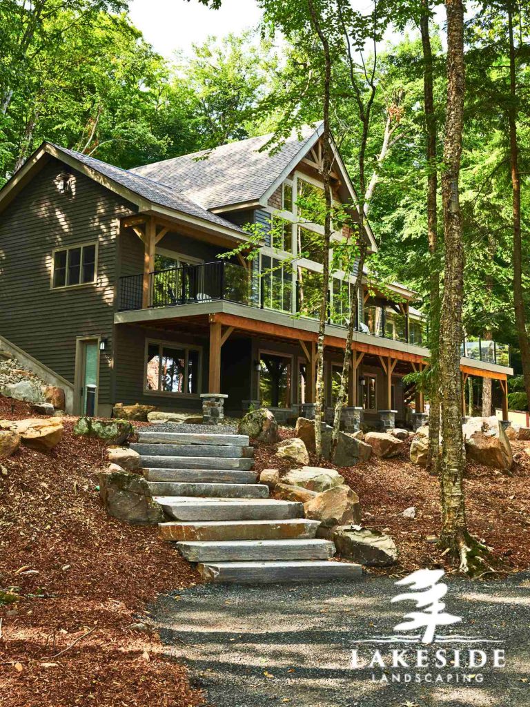 Beautiful Muskoka Cottage with wraparound deck, glass panels, stone steps and landing.